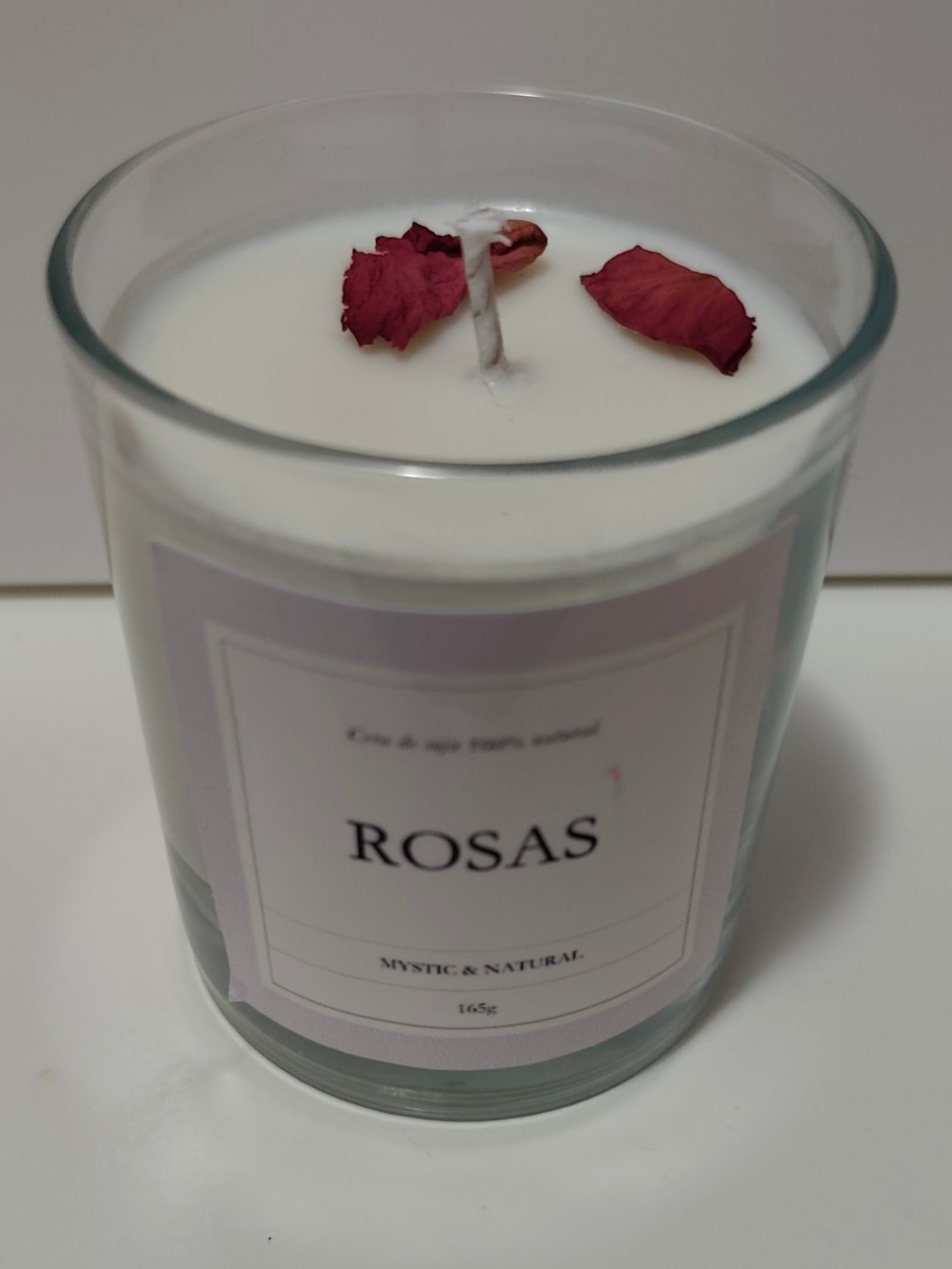 vela de cera de soja natural con aroma a rosas en vaso de  vidrio transparente de color blanco y con petalos decorativos hecho a mano en españa por mistica y natural wax